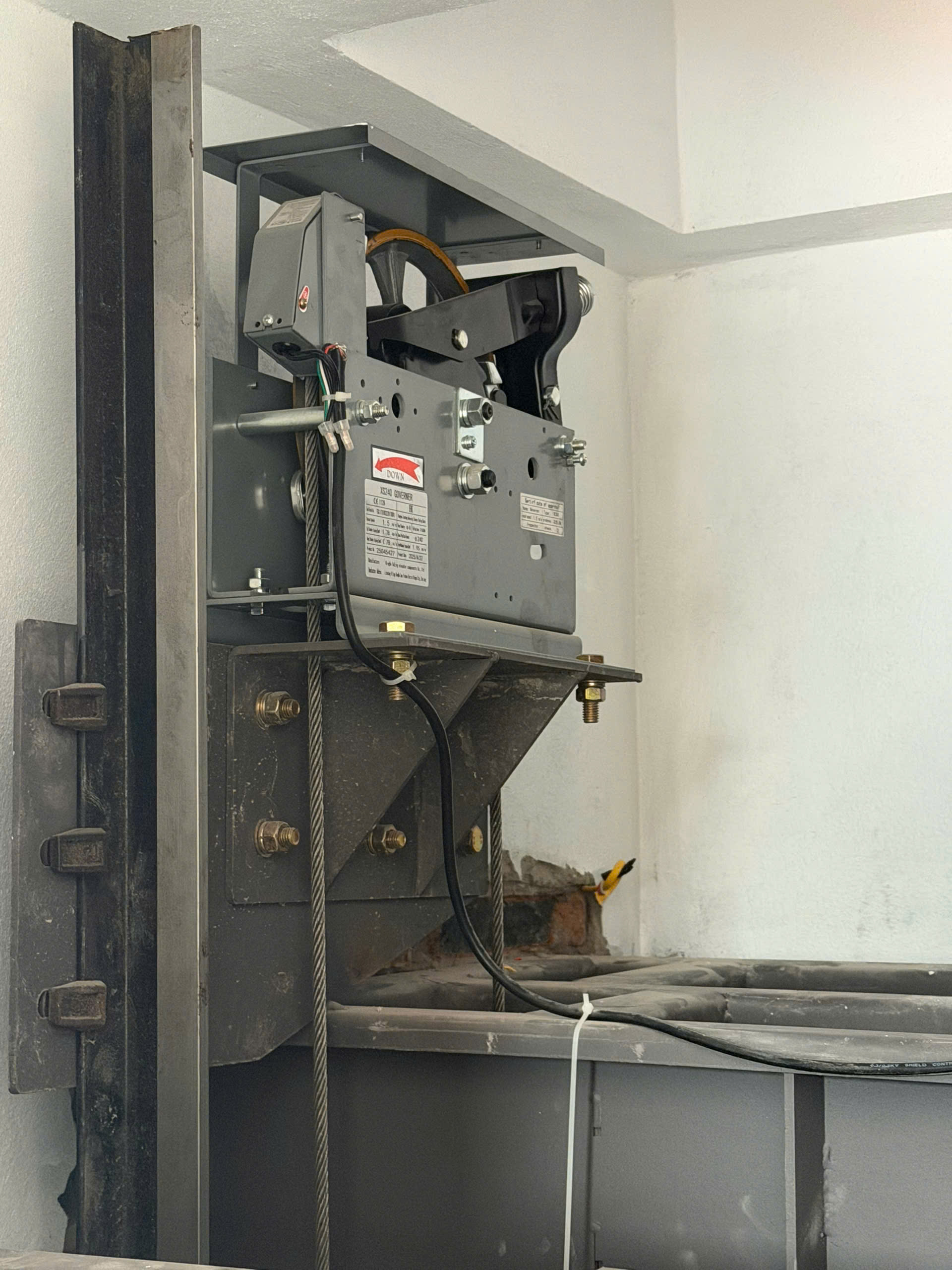 Cụm máy tời thang máy với cáp thép và dây điện lắp đặt trong giếng thang